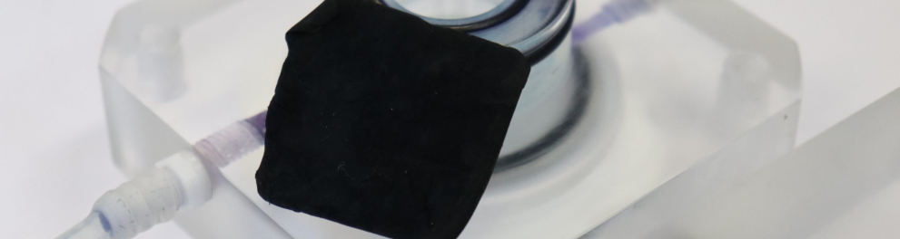 Um pedaço quadrado de membrana negra em cima de uma superfície branca