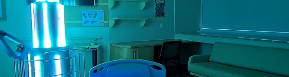 Um ambiente que parece ser um quarto de hospital está sendo esterilizado por um aparelho robótico
