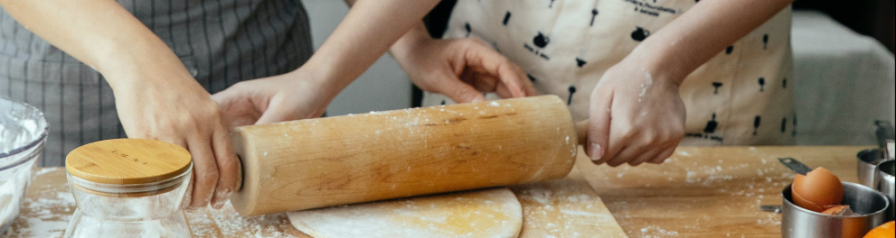 Duas pessoas abrindo uma massa de pizza.