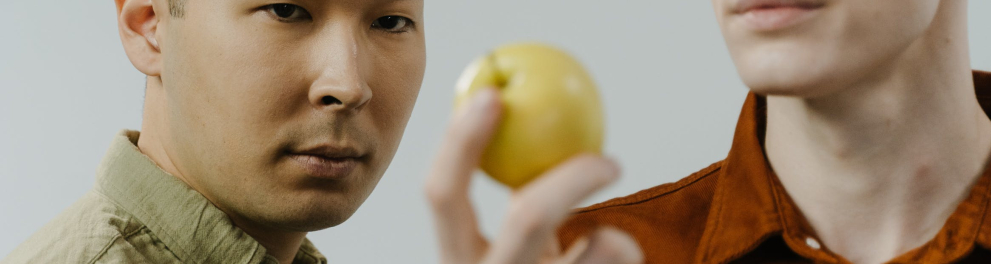 Dois homens olhando para uma fruta.
