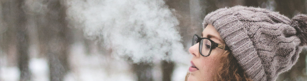 Mulher soltando fumaça pela boca no frio