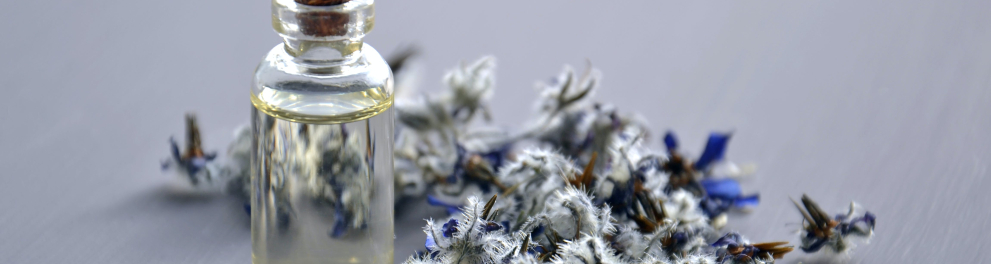 Um vidro com um liquido e flores ao lado