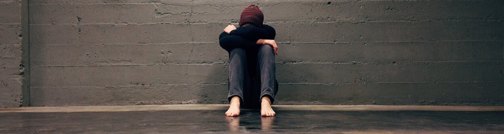 Uma pessoa no chão sentada com a cabeça apoiada em suas mãos