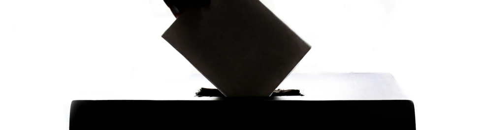 Uma mão colocando um voto em uma caixa