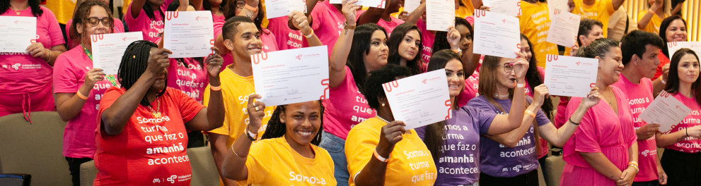 Várias pessoas seguram certificados com as mãos erguidas.