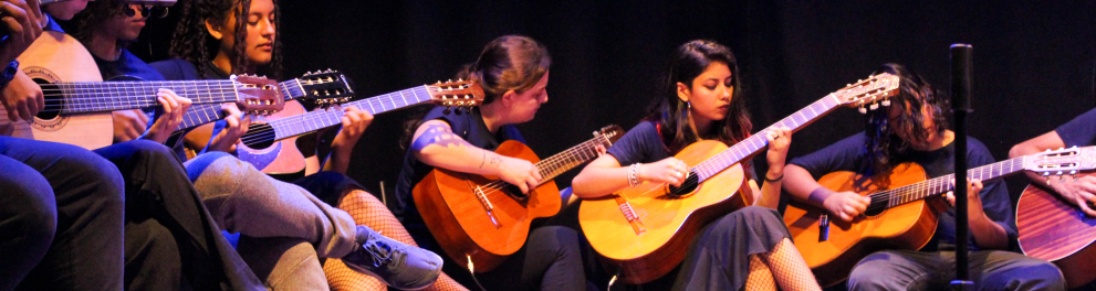 Pessoas tocando violão diante de um fundo escuro.