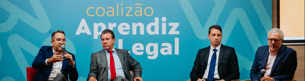 Quatro homens sentados. Todos de terno.