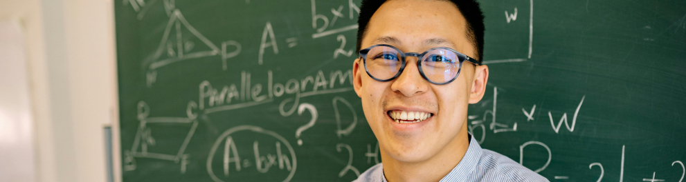 um professor sorrindo e perto da lousa