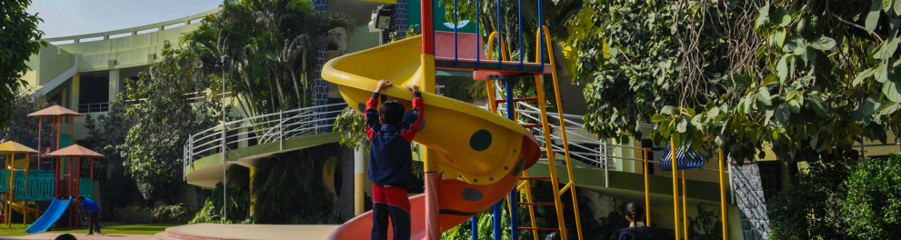 A imagem mostra crianças brincando no parquinho de uma escola