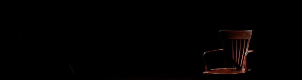A imagem mostra uma cadeira vazia sob a luz de um holofote