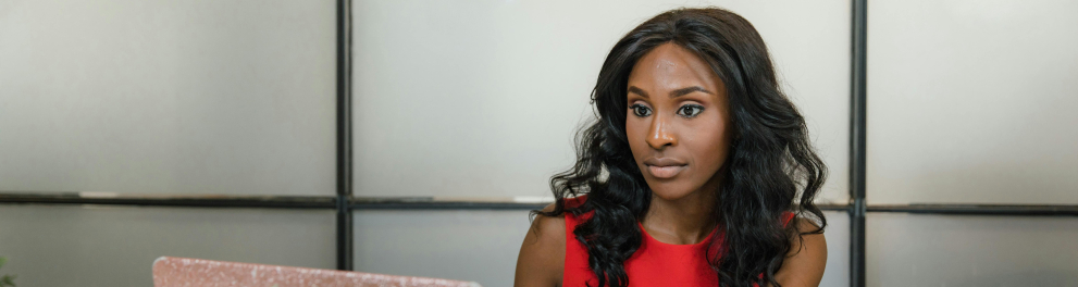 A imagem mostra uma mulher negra sentada usando um notebook