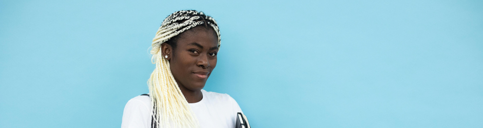 A imagem mostra uma jovem negra segurando um caderno e carregando uma mochila escolar