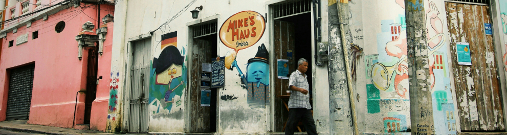 A imagem mostra um homem andando em uma calçada no bairro de Santa Teresa no Rio de Janeiro
