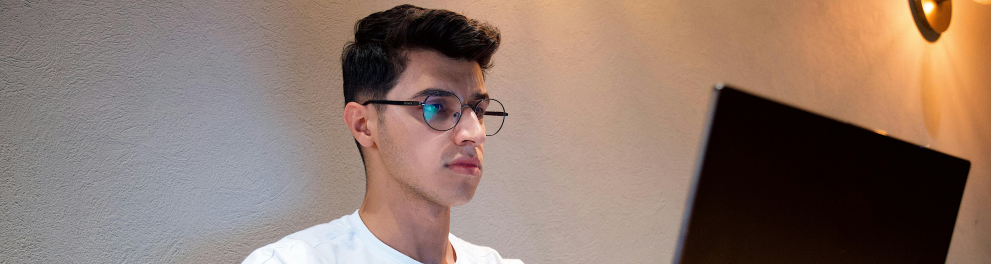 A imagem mostra um jovem rapaz usando um notebook