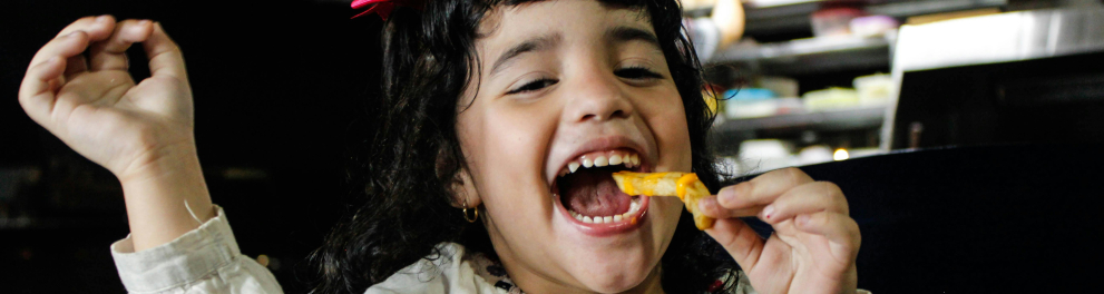 Uma criança comendo batata frita e bebendo refrigerante