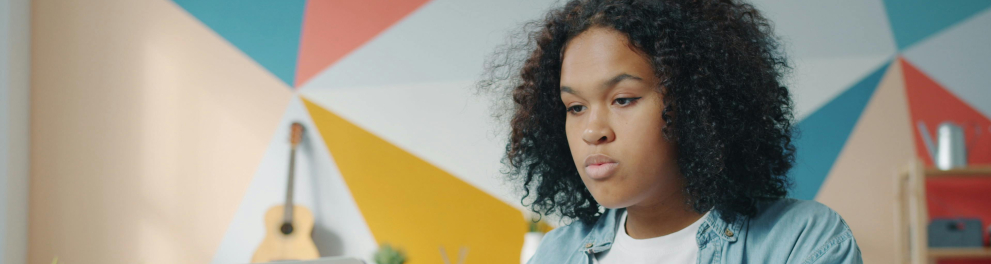 A imagem mostra uma jovem negra usando um notebook 