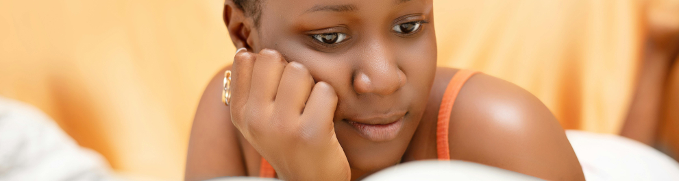 A imagem mostra uma jovem lendo um livro com a mão apoiada em seu rosto