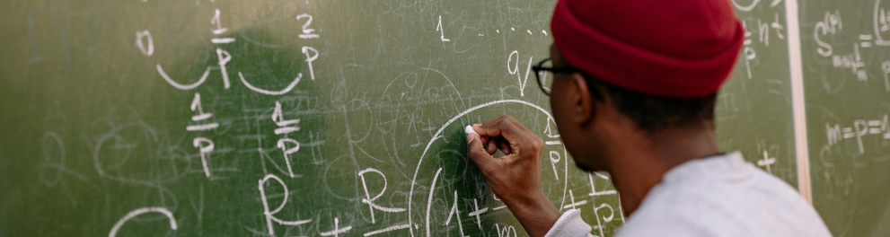 A imagem mostra um homem escrevendo em um quadro negro