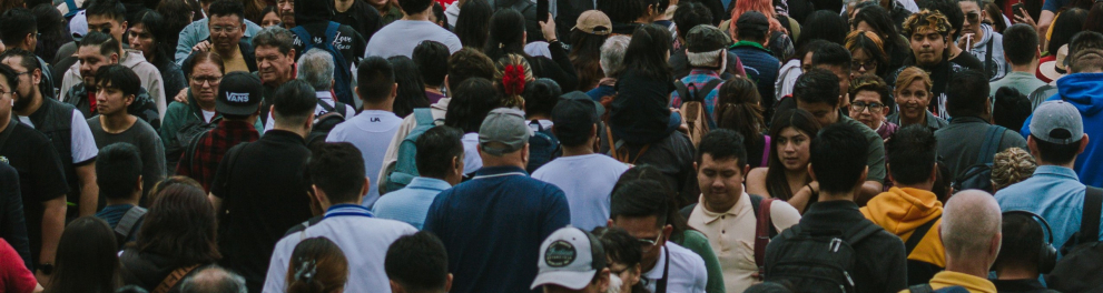A imagem mostra uma rua com diversas pessoas atravessando nos dois sentidos