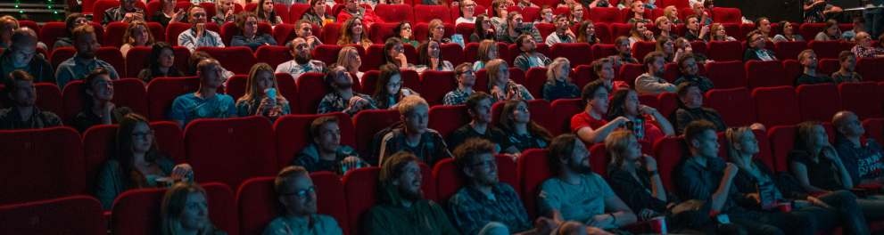 A imagem mostra um cinema com diversas pessoas