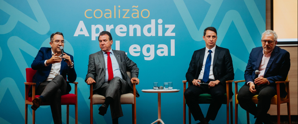 Quatro homens sentados. Todos de terno.