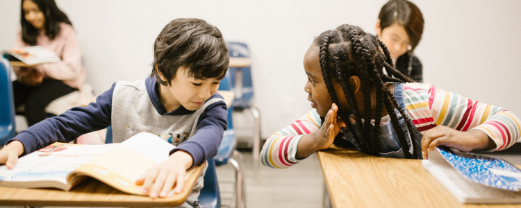 Duas crianças, um menino e uma menina, conversam na sala de aula.