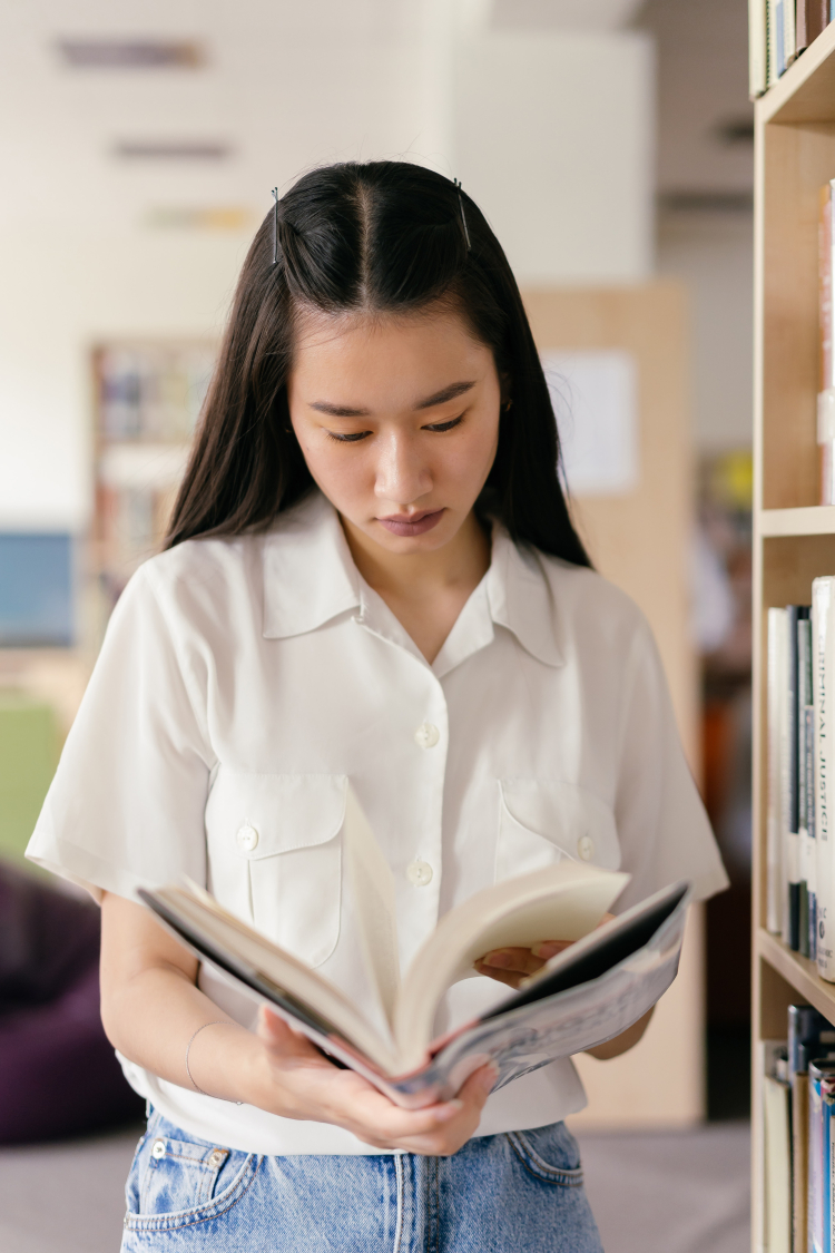 menina com um livro nas mãos em um biblioteca