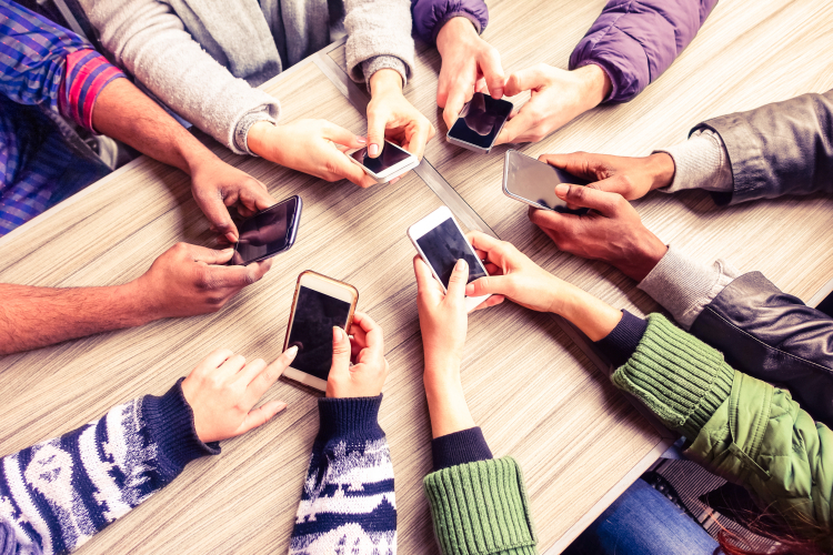 Várias pessoas segurando celulares em cima de uma mesa