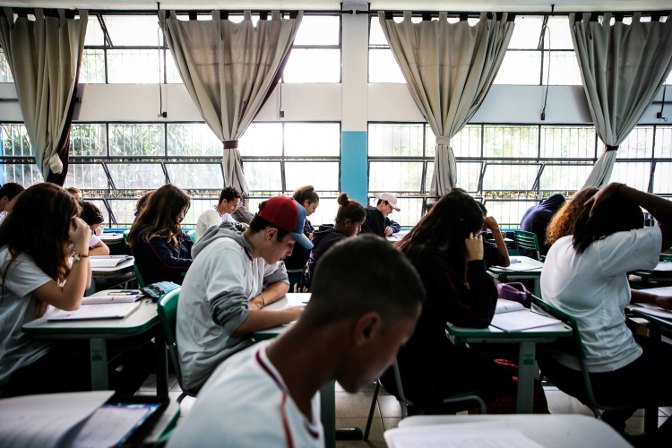 Uma sala de aula com alunos sentados e concentrados em seus livros