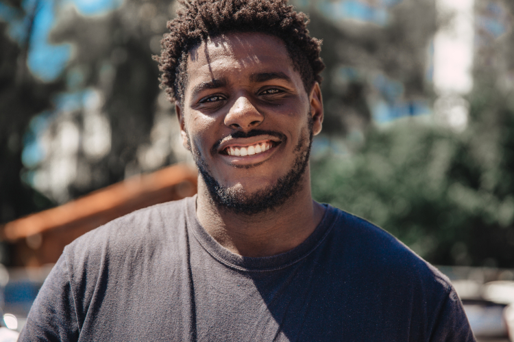 Um rapaz negro sorrindo para a foto