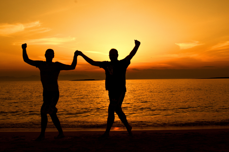 Duas pessoas de costas na praia no pôr do sol