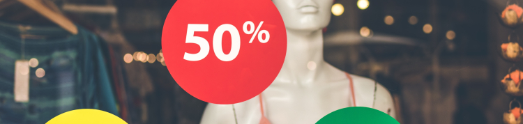 Adesivos mostrando taxas de porcentagem colados em uma vitrine de loja. Podemos ver um manequim atrás da vidraça da loja