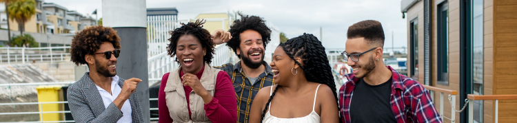 Cinco pessoas jovens e estão caminhando sorridentes e interagindo entre si em direção a quem bateu a foto