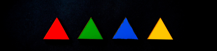 Quatro triângulos lado a lado sobre um fundo preto. Os triângulos são vermelho, verde, azul e amarelo respectivamente e possuem mesmo tamanho