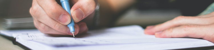 Uma pessoa escrevendo em um caderno com uma caneta