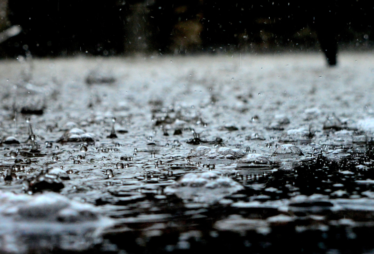 Imagem de pingos de chuva caindo sobre poça d'água à noite