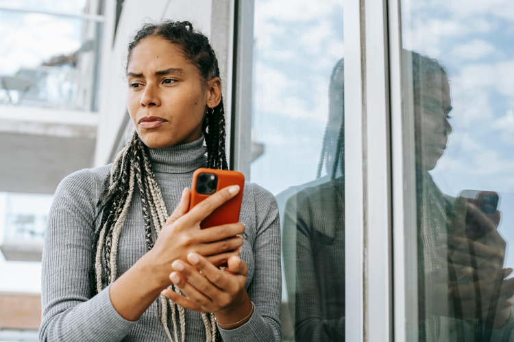 Uma mulher com o celular na mão em dúvida