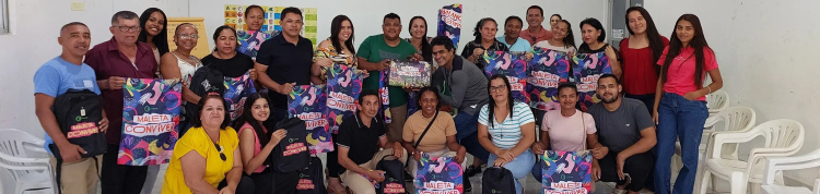 Diversas pessoas, de pé e agachadas, seguram suas Maletas Conviver.